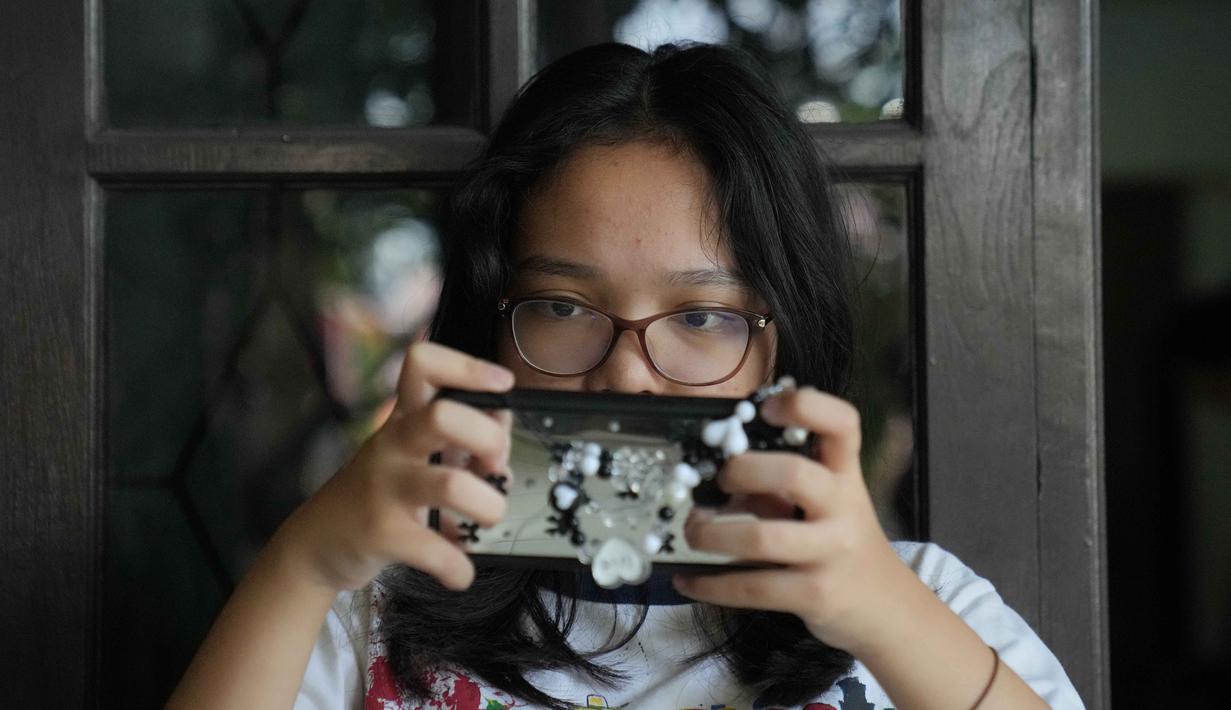 Meutya Hafid menambahkan bahwa semua platform digital yang berbisnis di Indonesia untuk segera menyelaraskan produk, fitur, dan layanan sesuai dengan peraturan yang berlaku. Tampak dalam foto, Maura Munthe memainkan permainan daring (online game platform), Roblox, melalui smartphone di rumahnya, Jakarta, 14 Maret 2026. (AP Photo/Dita Alangkara)