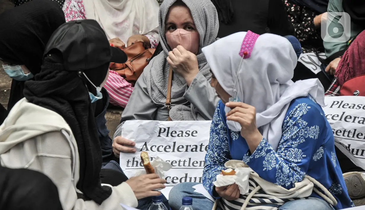 Pencari suaka asal Afghanistan membawa poster tuntutan di depan Kantor UNHCR, Jakarta, Senin (15/11/2021).  Ratusan pencari suaka tersebut menuntut segera dipindahkan ke negara ketiga yang terbebas dari konflik perang setelah lebih 10 tahun mengungsi di Indonesia. (merdeka.com/Iqbal S Nugroho)