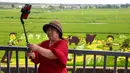 Seorang wanita berswafoto dengan latar belakang sawah bergambar yang dibuat dari berbagai varietas padi di Shenyang, Provinsi Liaoning, China, 17 Agustus2021. (STR/AFP)