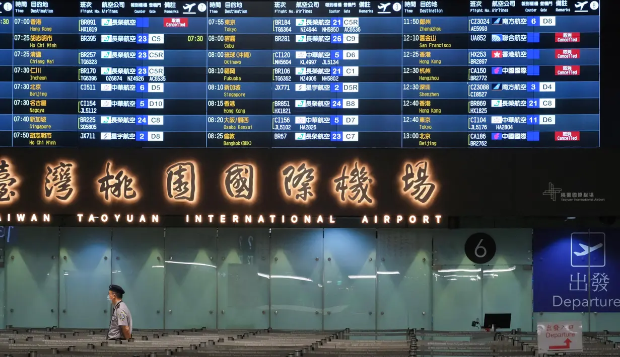 Seorang petugas keamanan berjalan melewati papan informasi yang menunjukkan beberapa penerbangan yang dibatalkan di bandara internasional Taoyuan pada tanggal 2 Oktober 2024. (Tommy WANG/AFP)