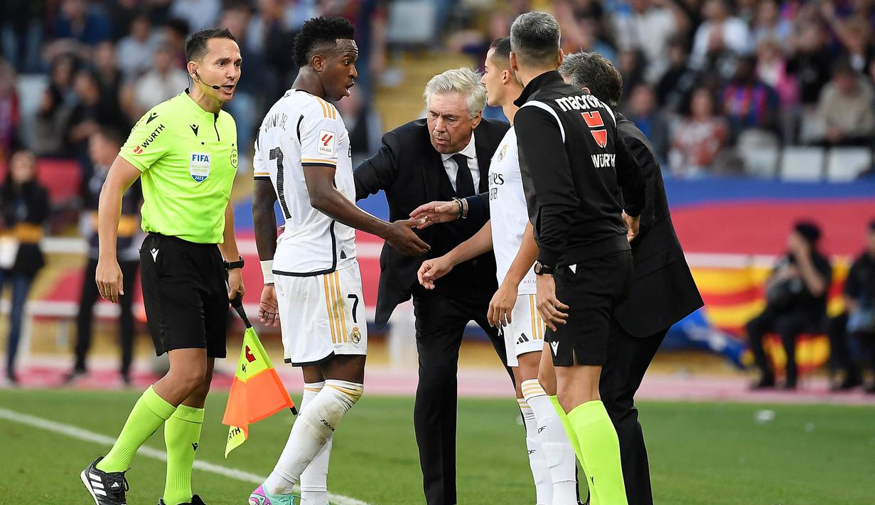 Ancelotti yang melihat kejadian itu pun geram atas perbuatan Vinicius. Ia segera menarik pemainnya untuk keluar lapangan agar pertandingan dapat berjalan kembali. Asisten wasit yang melihat kejadian tersebut juga segera memperingatkan Vinicius. (AFP/Josep Lago)
