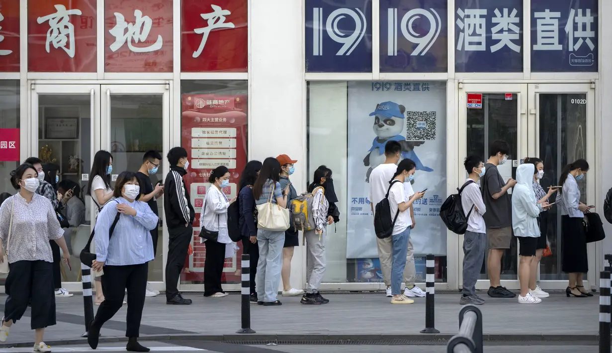 Karyawan yang mengenakan masker menunggu hasil tes COVID-19 mereka diperiksa untuk memasuki gedung perkantoran di kawasan pusat bisnis di Beijing, China, Selasa (31/5/2022). Otoritas Shanghai mengatakan mereka akan mengambil beberapa langkah besar pada Rabu untuk membuka kembali kota terbesar di China setelah dua bulan penguncian COVID-19. (AP Photo/Mark Schiefelbein)