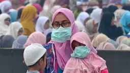 Umat muslim mengenakan masker saat mendengarkan ceramah usai melaksanakan salat Idul Adha di halaman Masjid Raya Annur, Kota Pekanbaru, Riau, Minggu (11/8/2019). Kabut asap imbas kebakaran hutan dan lahan (karhutla) menyelimuti pelaksanaan salat Idul Adha 2019 di Pekanbaru. (Wahyudi/AFP)