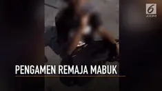 Seorang pengamen remaja tengah menenggak minuman keras di tepi jalan.