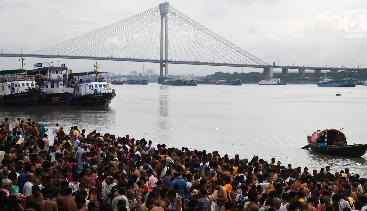 Ratusan umat Hindu melakukan ritual 'Tarpan' mempersembahkan doa kepada leluhur mereka pada hari terakhir Pitrupaksh di tepian Sungai Gangga di Kolkata (19/9). Dalam mitologi Hindu Hari Pitrupaksh juga disebut 'Mahalaya'. (AFP Photo/Dibyangshu Sarkar)