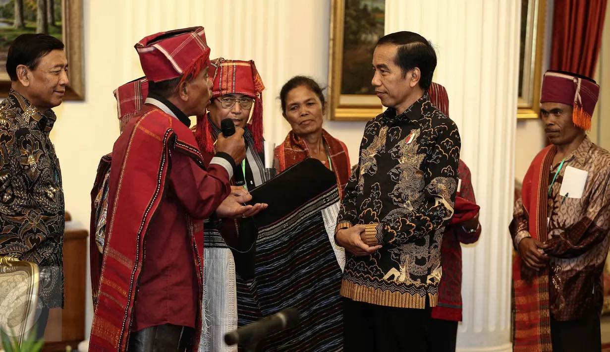 Pemangku Hutan Adat dari Tombak Haminjon (Kemenyan) Provinsi Sumatera Utara saat memberikan kain ulos kepada Presiden Joko Widodo (Jokowi) usai pencanangan pengakuan Hutan Adat di Istana Negara, Jakarta, Jumat (30/12). (Liputan6.com/Faizal Fanani)