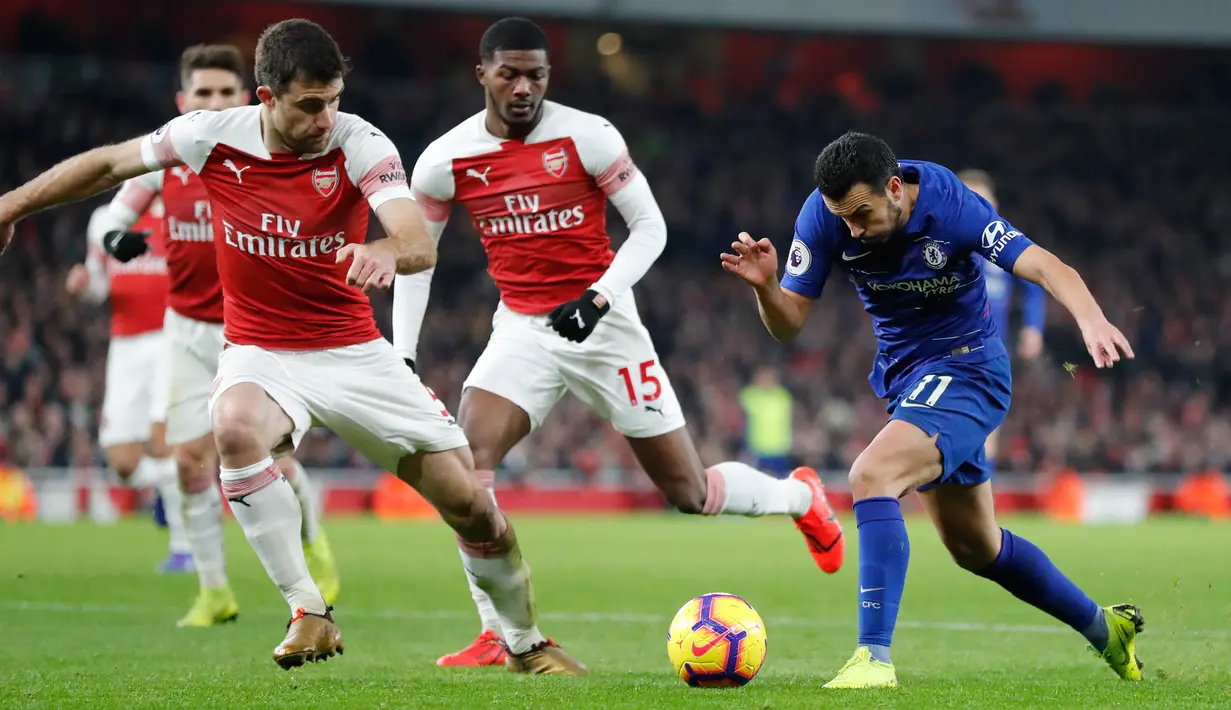 Gelandang Chelsea, Pedro berusaha melewati bek Arsenal, Sokratis Papastathopoulos selama pertandingan lanjutan Liga Inggris di stadion Emirates di London (19/1). Arsenal menang 2-0 atas Chelsea. (AP Photo/Frank Augstein)
