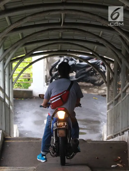 Pemotor melintasi jembatan penyeberangan orang (JPO) di kawasan Pasar Minggu, Jakarta, Rabu (24/4). Kurangnya kesadaran akan tertib berlalu lintas menyebabkan para pemotor itu nekat melintasi JPO, meskipun dapat merugikan hak pejalan kaki. (Liputan6.com/Immanuel Antonius)