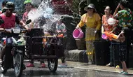 Warga menghujani pengendara sepeda motor dengan air saat merayakan Festival Songkran atau Tahun Baru Thailand di Narathiwat, Thailand, 13 April 2019. Festival ini rutin diselenggarakan setiap tanggal 13-15 April setiap tahunnya. (Madaree TOHLALA/AFP)