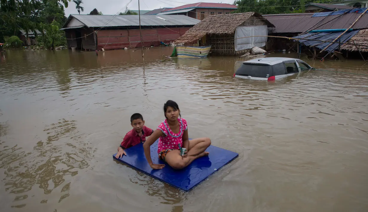 Warga menggunakan rakit menerobos banjir yang merendam di kecamatan Mawlamyine, negara bagian Mon, Myanmar (18/6). Hujan merendam rumah warga dan memaksa ratusan orang mengungsi. (AFP PHOTO / Ye Aung Thu)