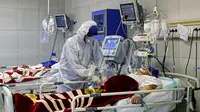Petugas medis merawat seorang pasien yang terinfeksi virus corona atau COVID-19 di sebuah rumah sakit di Teheran, Iran, Minggu (1/3/2020). Kasus virus corona di Iran mengalami lonjakan tajam dalam beberapa hari. (Ali Shirband/Mizan News Agency via AP)