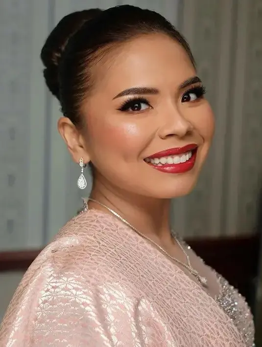 Makeup bold dengan lipstik merah dan riasan mata bold pun dikenakan Felicia. Ia melengkapi penampilan dengan perhiasan kalung dan anting-anting.  [@djanurms.mua/@myrnamyura]