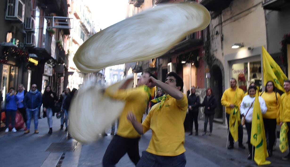 Anggota Pizzaioli Acrobats Coldiretti melakukan Pizzaioli atau seni memutar adonan piza di Naples, Italia, 7 Desember 2017. Seni memutar adonan piza milik masyarakat Napoli reSmi masuk dalam daftar "warisan budaya tak benda" UNESCO. (Tiziana FABI/AFP)