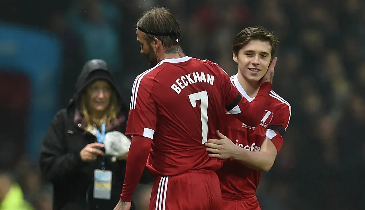 Pemain Great Briitain, David Beckham, digantikan putranya Brooklyn pada laga amal melawan World XI di Old Trafford, Inggris, Sabtu (14/11/2015) dini hari WIB. (AFP Photo/Paul Ellis)