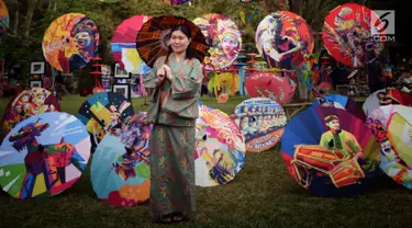 Pengunjung berfoto di sekitar dekorasi payung pada acara Festival Payung Indonesia 2018 di Taman Lumbini, Komplek Candi Borobudur, Magelang, Jumat (7/9). Acara tahunan kali ini bertema 'Sepayung Indonesia, Lalitavistara'. (Liputan6.com/Gholib)