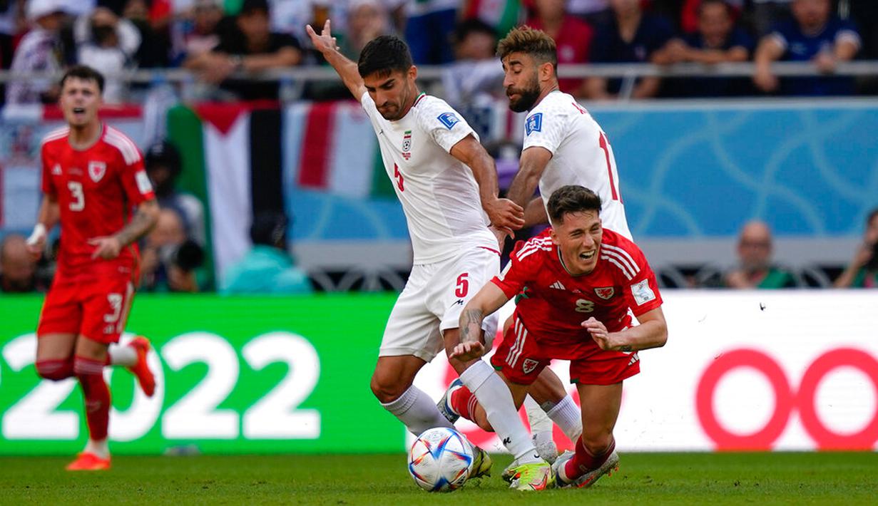 Pemain Iran Milad Mohammadi (kiri) berebut bola dengan pemain Wales Harry Wilson pada pertandingan sepak bola Grup B Piala Dunia 2022 di Stadion Ahmad Bin Ali, Al Rayyan, Qatar, Jumat (25/11/2022). Iran mengalahkan Wales dengan skor 2-0. (AP Photo/Frank Augstein)