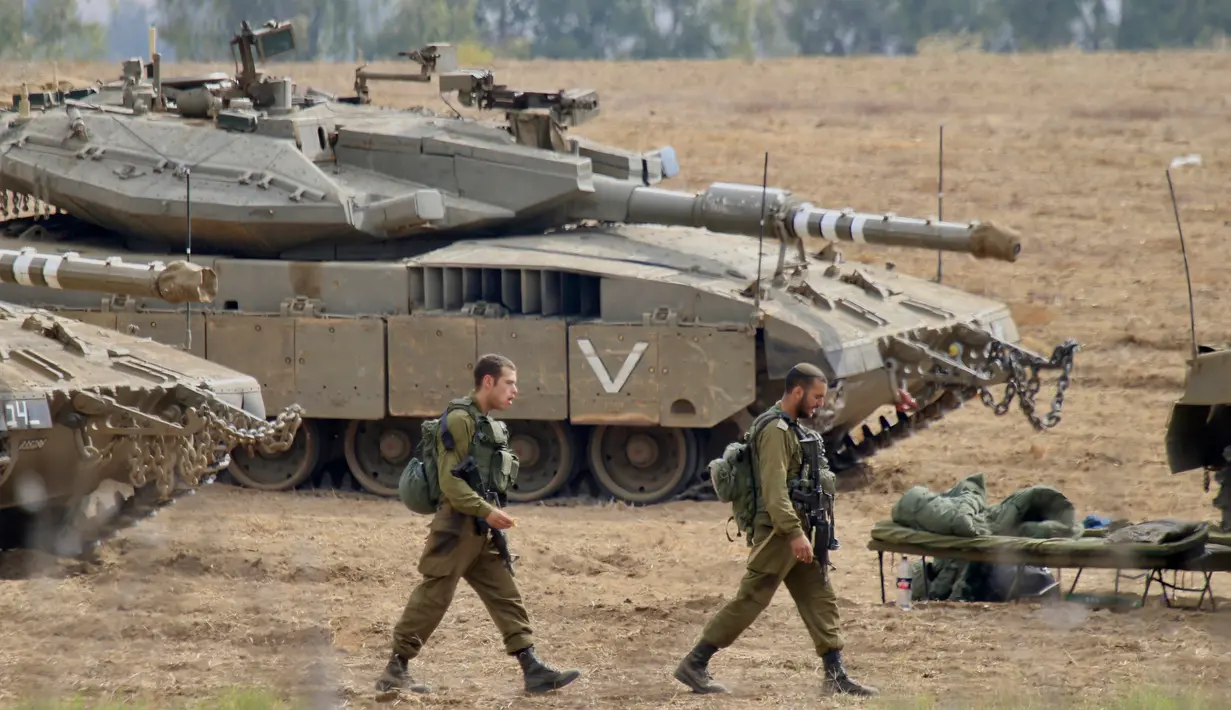 <p>Tentara Israel berjalan melewati tank di dekat perbatasan Gaza-Israel, Jumat (19/10). PM Benjamin Netanyahu berjanji bakal mengambil tindakan tegas apabila warga Palestina masih terus melancarkan serangan ke wilayah Israel. (AP Photo/Ariel Schalit)</p>