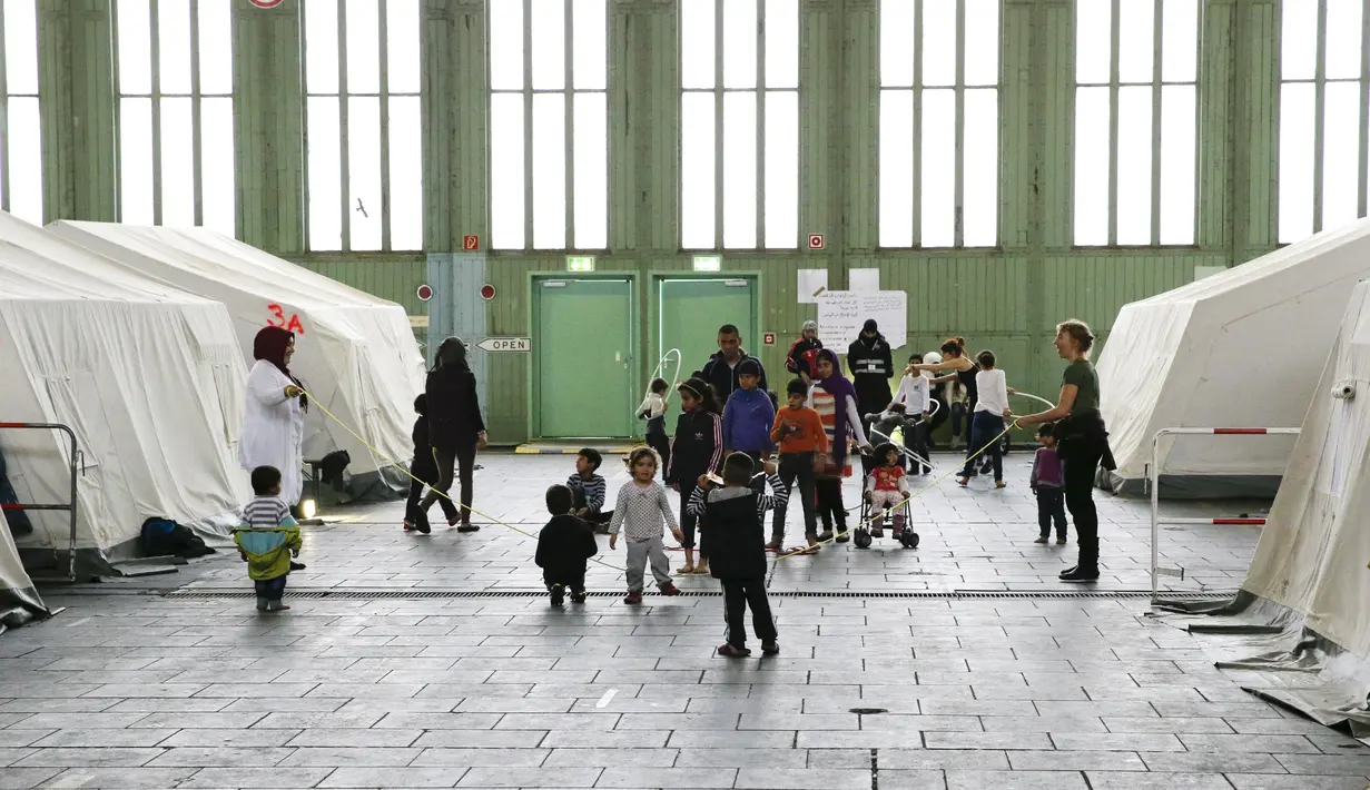 Anak-anak bermain di dekat tenda yang didirikan bagi para migran di dalam hanggar bekas bandara Tempelhof di Berlin, Jerman, Rabu (9/12/2015). Jerman menerima satu juta migran dari beberapa negara yang sedang dilanda perang. (REUTERS/Fabrizio Bensch)