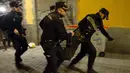 Polisi Spanyol membawa seorang pria saat bentrokan terjadi di Madrid, Spanyol, Kamis (15/3). Bentrokan berawal dari aksi protes imigran atas meninggalnya seorang pedagang jalanan asal Senegal. (AFP Photo/Olmo Calvo)