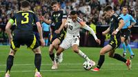 Gelandang Timnas Jerman, Jamal Musiala, berduel dengan pemain&nbsp;Skotlandia pada laga perdana Grup A Euro 2024 di Fussball Arena, Munchen, Sabtu (15/6/2024) dini hari WIB. Dalam pertandingan itu, Jerman menang 5-1atas Skotlandia. (AFP/Miguel Medina).&nbsp;