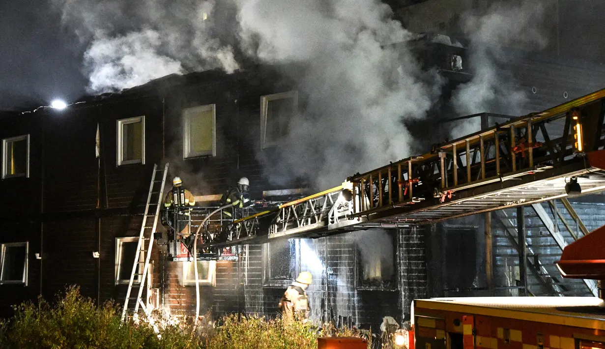 Asap mengepul di tempat pengungsi di Fagersjo yang terbakar, Stockholm, Swedia pada Minggu (16/10) malam. Petugas pemadam kebakaran berusaha memadamkan api yang berkobar dari dalam gedung. (REUTERS/TT News Agency / Johan Nilsson)