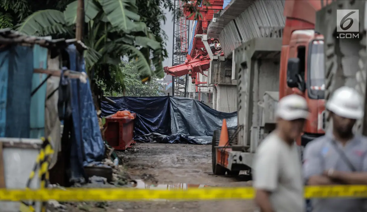 Pekerja berjaga di dekat garis polisi usai ambruknya crane pengerjaan proyek double-double track kereta api di Jatinegara, Jakarta, Minggu (4/2). Jenazah korban tewas sudah dibawa ke rumah sakit dengan mobil ambulans.  (Liputan6.com/Faizal Fanani)