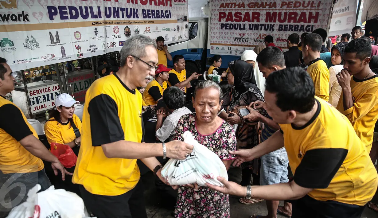 Senior Artha Graha Peduli Heka Hertanto (kiri) memberikan sembako pada Pasar Murah Ramadan 2016 di kawasan Pasar Benhil, Jakarta, Minggu (5/6/2016). Pasar Murah Ramadan 2016 ini diadakan oleh Artha Graha Peduli. (Liputan6.com/Faizal Fanani)