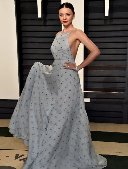 Dress tanpa lengan berwarna biru langit dan bermotif bunga-bunga ini berhasil membuat tampilan Miranda Kerr tampak elegan. Terlebih dengan lipstick berwarna merah yang membuat wajahnya semakin bersinar. (AFP/Bintang.com)