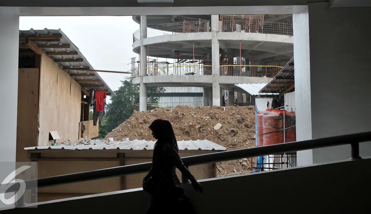 Warga melintas di depan lokasi pembangunan Blok III Pasar Senen, Jakarta, Kamis (20/10). Blok III Pasar Senen nantinya akan digunakan bagi para pedagang yang menjadi korban kebakaran hebat pada 25 April 2014 lalu. (Liputan6.com/Yoppy Renato)