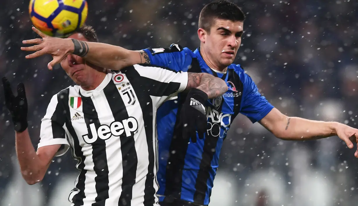 Pemain Juventus Mario Mandzukic berebut bola dengan bek Atalanta Gianluca Mancini pada laga leg kedua semifinal Coppa Italia di Allianz Stadium, Rabu (28/2). Juventus memastikan diri lolos ke final setelah menang 1-0. (MARCO BERTORELLO/AFP)