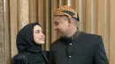 Pedangdut berusia 20 tahun itu tampil elegan dengan kebaya hitamnya, beserta hijab warna senada. Sementara itu, sang suami tampil gagah kenakan beskap dan blangkon. Keduanya tetap serasi dengan perpaduan bawahan kain batik, meski berbeda motif. (Liputan6.com/IG/@putriisnari3)