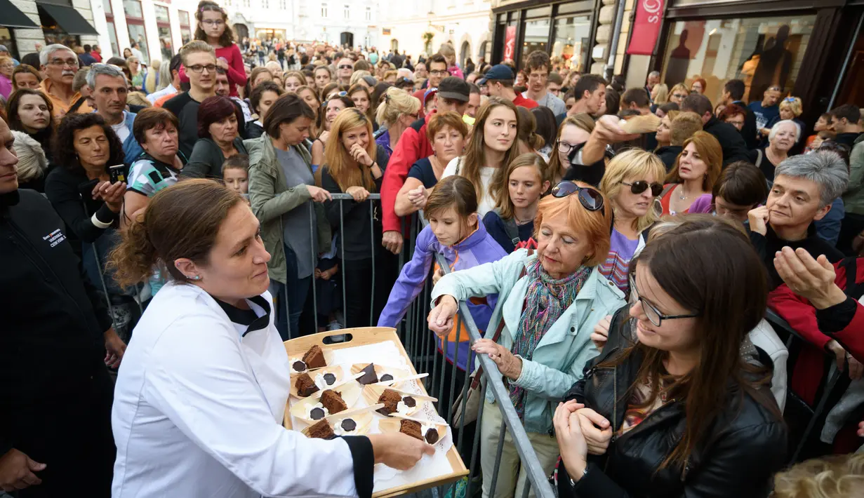 Seorang koki membagikan potongan kue cokelat atau dikenal sebagai Sacher Torte, kepada warga sekitar di Ljubljana, Slovenia, Rabu (21/9). Kue dengan diameter 3,5 meter ini diklaim menjadi Sacher Torte terbesar di dunia. (AFP PHOTO/Jure MAKOVEC)