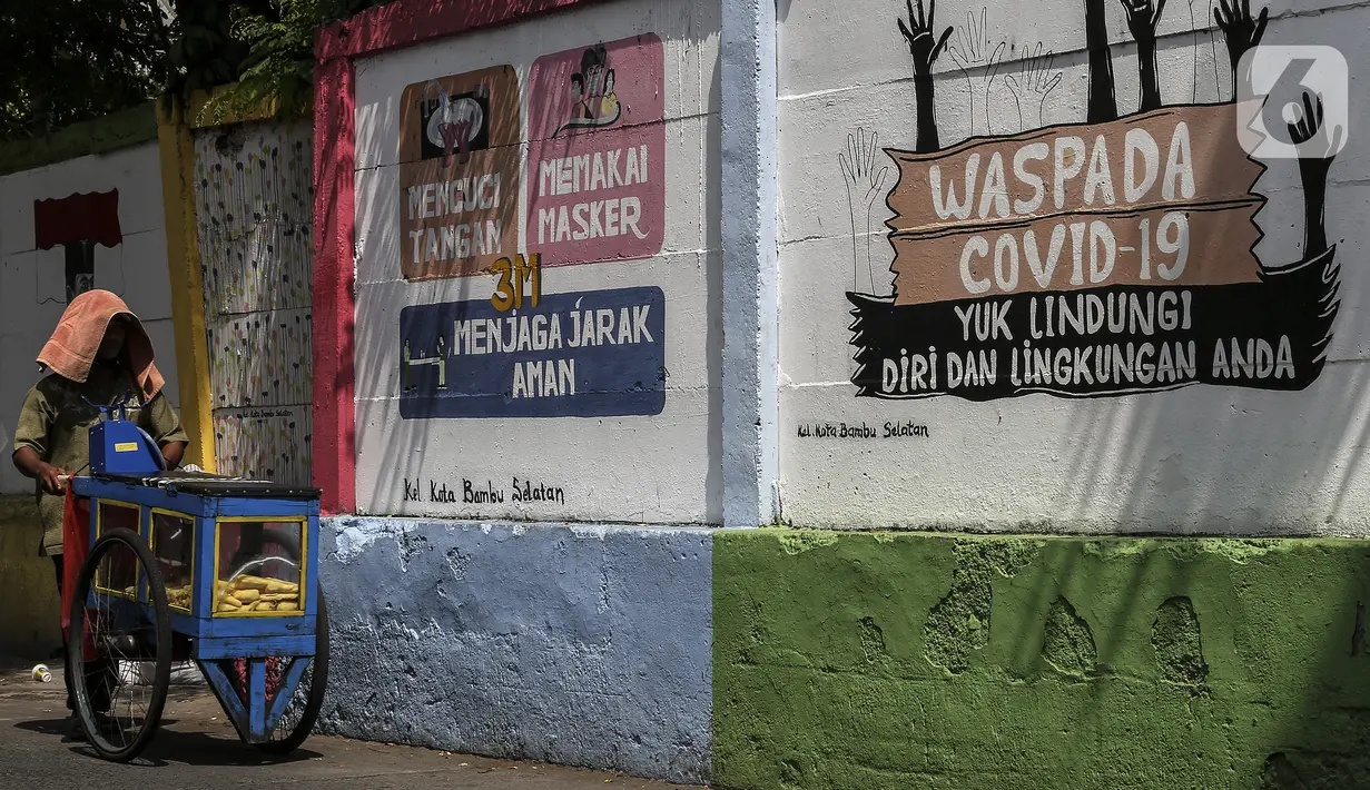 Pedagang melintas dekat mural imbauan untuk mematuhi protokol kesehatan di Jakarta, Selasa (20/7/2021). Kementerian Kesehatan mencatat pasien COVID-19 di Jakarta yang sembuh pada 19 Juli 2021 sebanyak 12.674 atau meningkat dibandingkan 18 Juli 2021 sebanyak 11.857 orang. (Liputan6.com/Johan Tallo)