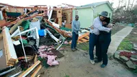 Phyllis Evans mendapat pelukan dari Harvey Payne setelah melihat kondisi rumahnya yang dihantam tornado di Holly Springs, Mississipi, Kamis (24/12). Badai tornado menerjang wilayah Amerika Serikat bagian selatan dan menewaskan 11 orang.  (REUTERS)