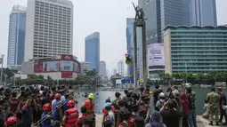Sejumlah personel keamanan dan petugas penyelamat mengamati proses penurunan aktivis Greenpeace Indonesia yang memanjat Patung Selamat Datang di Bundaran Hotel Indonesia, Jakarta, Selasa (20/10/2026). Aksi tersebut digelar bertepatan dengan dua tahun pelantikan Presiden Prabowo Subianto. Para aktivis mendesak pemerintah mengambil langkah untuk mengatasi krisis iklim yang kian memburuk serta kenaikan biaya hidup. (BAY ISMOYO/AFP)