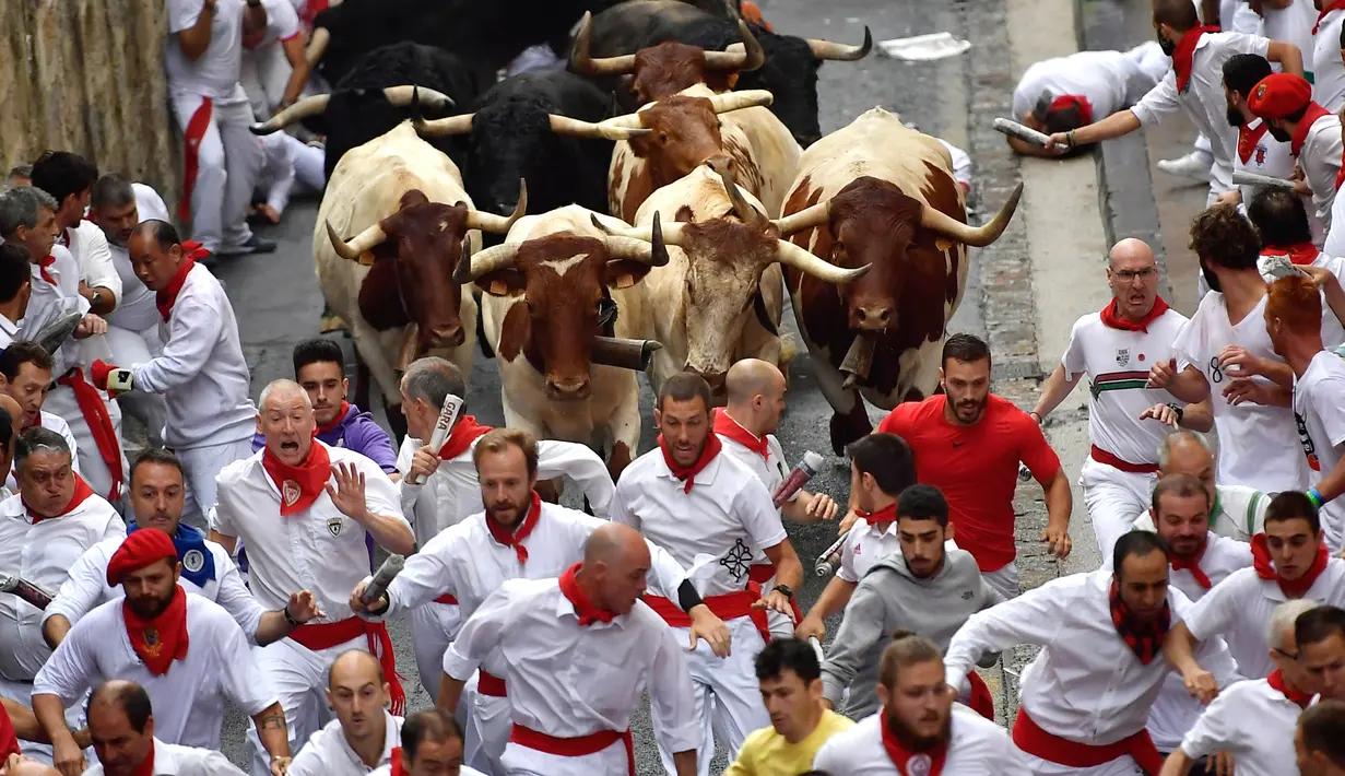 Peserta bersuka ria berlari di samping banteng selama Festival San Fermin di Pamplona, Spanyol, Senin (9/7). Festival berbahaya ini diikuti oleh peserta dari seluruh penjuru dunia. (AP Photo/Alvaro Barrientos)