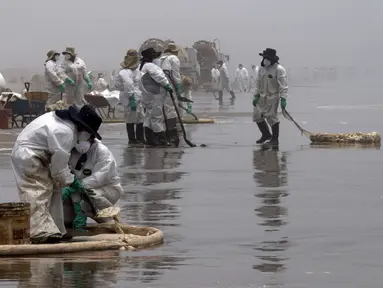 Petugas kebersihan bekerja untuk mengeluarkan minyak dari Pantai Cavero di Callao, Peru, 26 Januari 2022. Pembersihan Pantai Cavero dari tumpahan minyak kapal tanker Mare Doricum yang dihantam gelombang akibat letusan gunung berapi Tonga masih terus dilakukan. (Cris BOURONCLE/AFP)