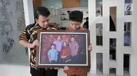 Muhammad Ivanka Rizaldi Nugroho (kiri) dan Muhammad Aufa Wikantyasa Nugroho (kanan) anak dari Kepala Pusat Data Informasi dan Humas BNPB Sutopo Purwo Nugroho melihat  foto keluarga di rumah duka Raffles Hils, Cimanggis,  Depok, Jawa Barat, Minggu (7/7/2019). (Liputan6.com/Herman Zakharia)