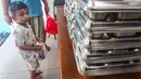 Seorang anak menemani ibunya mengambil makan bergizi gratis (MBG) untuk dikonsumsi di rumah di Posyandu kawasan Limo, Depok, Jawa Barat, Selasa (14/7/2025).