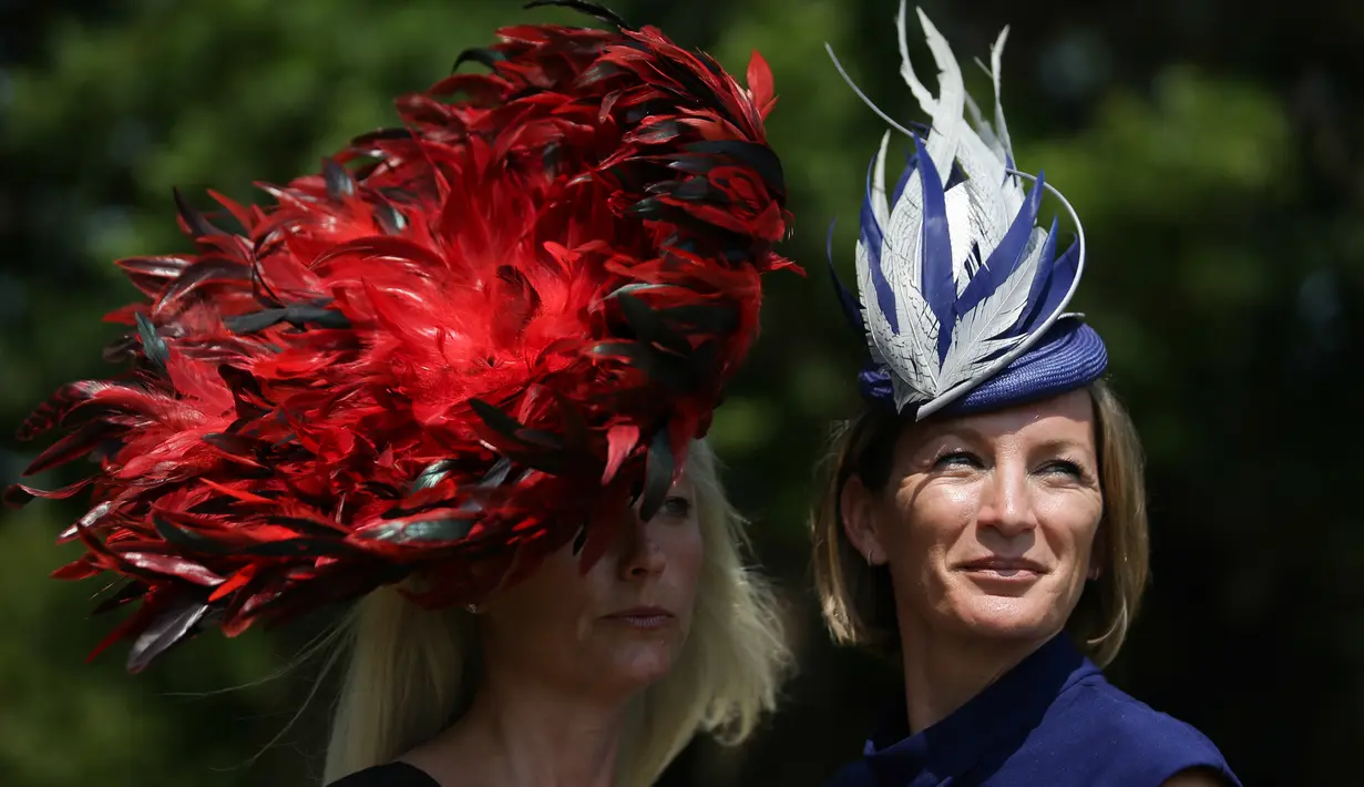 Dua wanita memakai hiasan kepala berpose saat tiba untuk menyaksikan balap kuda Royal Ascot horse di Ascot, London, (20/6). Balap kuda ini telah diadakan di Berkshire sejak tahun 1711. (AFP Photo/Daniel Leal-Olivas)