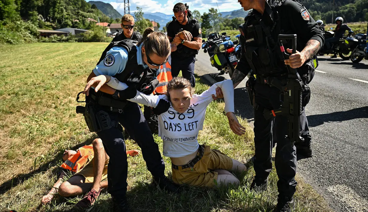 Polisi Prancis memindahkan sejumlah pengunjuk rasa lingkungan setelah aksi protes mereka menghentikan sementara balapan pada etape ke-10 Tour de France, antara Morzine dan Megeve, di Pegunungan Alpen Prancis, pada 12 Juli 2022. (AFP/Marco Bertorello)