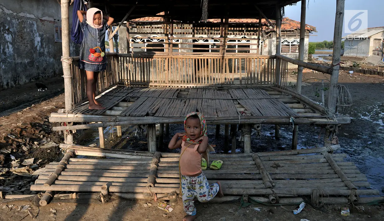 Anak-anak bermain di depan salah satu rumah yang ditinggalkan penghuni di Kampung Beting, Desa Pantai Bahagia, Muara Gembong, Kabupaten Bekasi, Jawa Barat pada 28 Juli 2019. (merdeka.com/Iqbal S Nugroho)