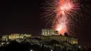 Kembang api meledak di atas kuil Parthenon kuno di bukit Acropolis saat perayaan Tahun Baru di Athena, Yunani, Minggu (1/1/2022). Saat pergantian tahun, orang akan beramai-ramai melihat pertunjukan kembang api di langit yang berwarna-warni dan saling bersahutan.  (AP Photo/Yorgos Karahalis)