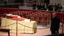 Jenazah mendiang Paus Emeritus Benediktus XVI disemayamkan saat Pastor Georg Gaenswein berdiri di sebelah kanan di Basilika Santo Petrus, Vatikan, Senin (2/1/2023). Benediktus XVI, teolog Jerman yang akan dikenang sebagai paus pertama dalam 600 tahun yang mengundurkan diri, telah meninggal pada 31 Desember 2022 di usia 95 tahun. (AP Photo/Andrew Medichini)
