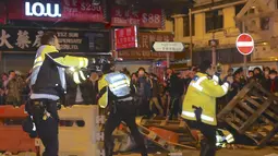 Petugas polisi (kiri) mengeluarkan pistol saat bentrok dengan sejumlah pengunjuk rasa di Mongkok, Hong Kong, Selasa (9/2). Bentrokan dimulai ketika pemerintah daerah mencoba untuk menertibkan PKL yang beroperasi. (REUTERS/E Weekly/Fu Chun-wai)
