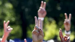 Sejumlah orang menunjukkan tanda perdamaian saat berkumpul untuk membentuk simbol perdamaian raksasa di New York Central Park , Selasa (6/10). Kegiatan yang diprakarsai janda Lennon, Yoko Ono itu menandai ulang tahun John Lennon ke-75.(REUTERS/Mike Segar)