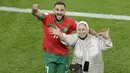 Pemain Maroko, Sofiane Boufal, merayakan kemenangan atas Portugal bersama ibunya pada laga perempat final di Stadion Al-Thumama, Sabtu (10/12/2022). (AFP/Juan Mabromata)