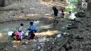 Warga mencuci pakaian dengan air dari lubang pada aliran Sungai Cihoe yang digunakan untuk memenuhi kebutuhan sehari-hari di Ridogalih, Cibarusah, Bekasi, Minggu (7/7/2019). Sudah lebih dari dua bulan, warga memanfaatkan sisa aliran sungai yang kotor akibat musim kemarau. (merdeka.com/Arie Basuki)