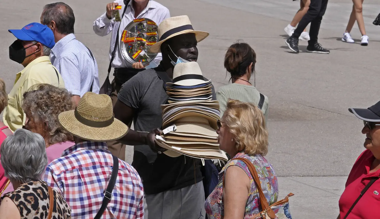 Seorang pria mencoba menjual topi untuk melindungi dari matahari kepada turis di pusat kota Madrid, Spanyol, Minggu (12/6/2022). Layanan cuaca Spanyol mengatakan massa udara panas dari Afrika utara memicu gelombang panas besar pertama di negara itu tahun ini dengan suhu diperkirakan naik hingga 43 derajat Celcius (109 derajat Fahrenheit) di area tertentu.  (AP Photo/Paul White)