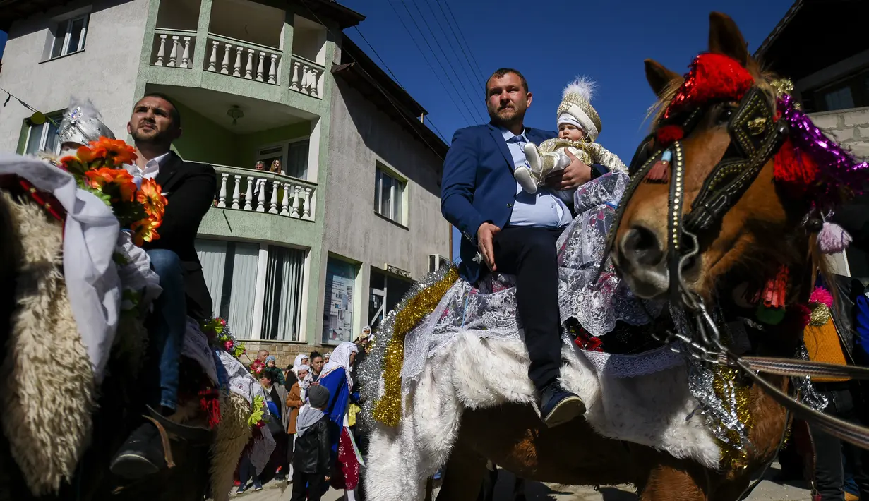 Seorang pria muslim Bulgaria menggendong putranya saat duduk di atas kuda selama upacara sunat massal untuk anak laki-laki di Desa Ribnovo, 11 April 2021. Penduduk Desa Ribnovo adalah muslim berbahasa Bulgaria, kadang-kadang disebut sebagai "Pomaks" atau "orang yang menderita". (Nikolay DOYCHINOV/AF